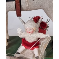 Snow angel on a sledge with 2 pigeons in front, size: 7,5 x 13 cm.